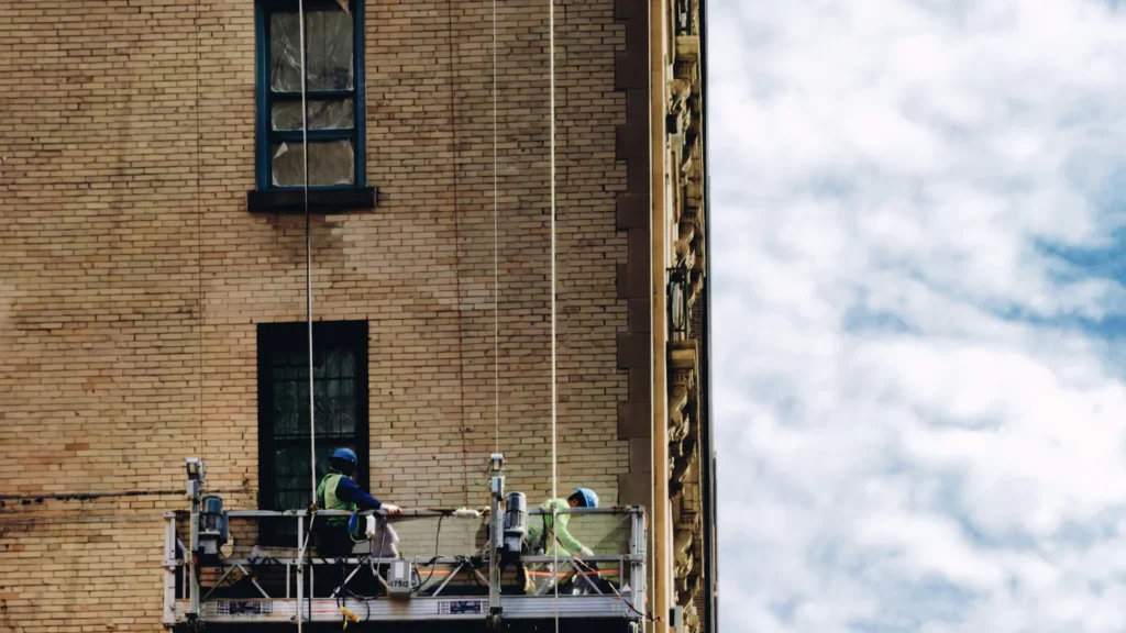 Workers on a suspended scaffold at a building facade, the kind of access a FISP close-up inspection needs