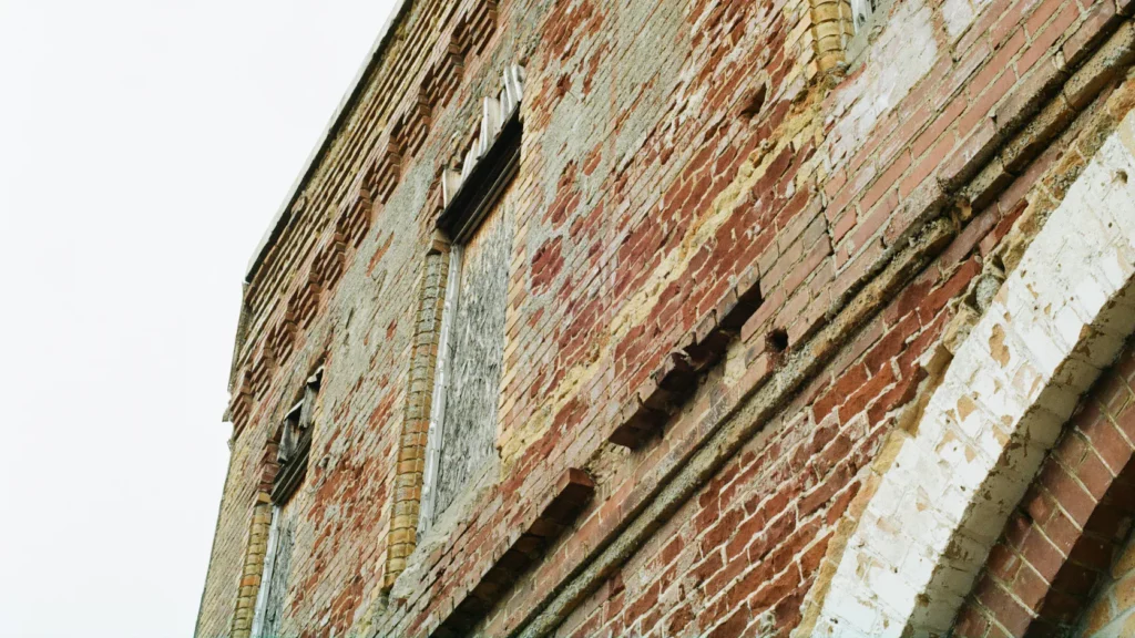 Weathered brick facade with cracked masonry around an arched window, the kind of damage fixed before a FISP inspection